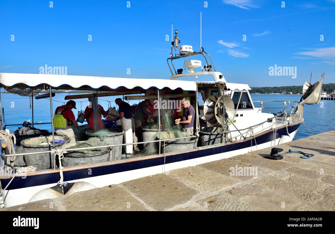 Nettoyage des filets de pêcheurs et réparer le bateau de pêche de la vieille ville historique de Rovinj en Istrie, Croatie sur la mer Adriatique Banque D'Images