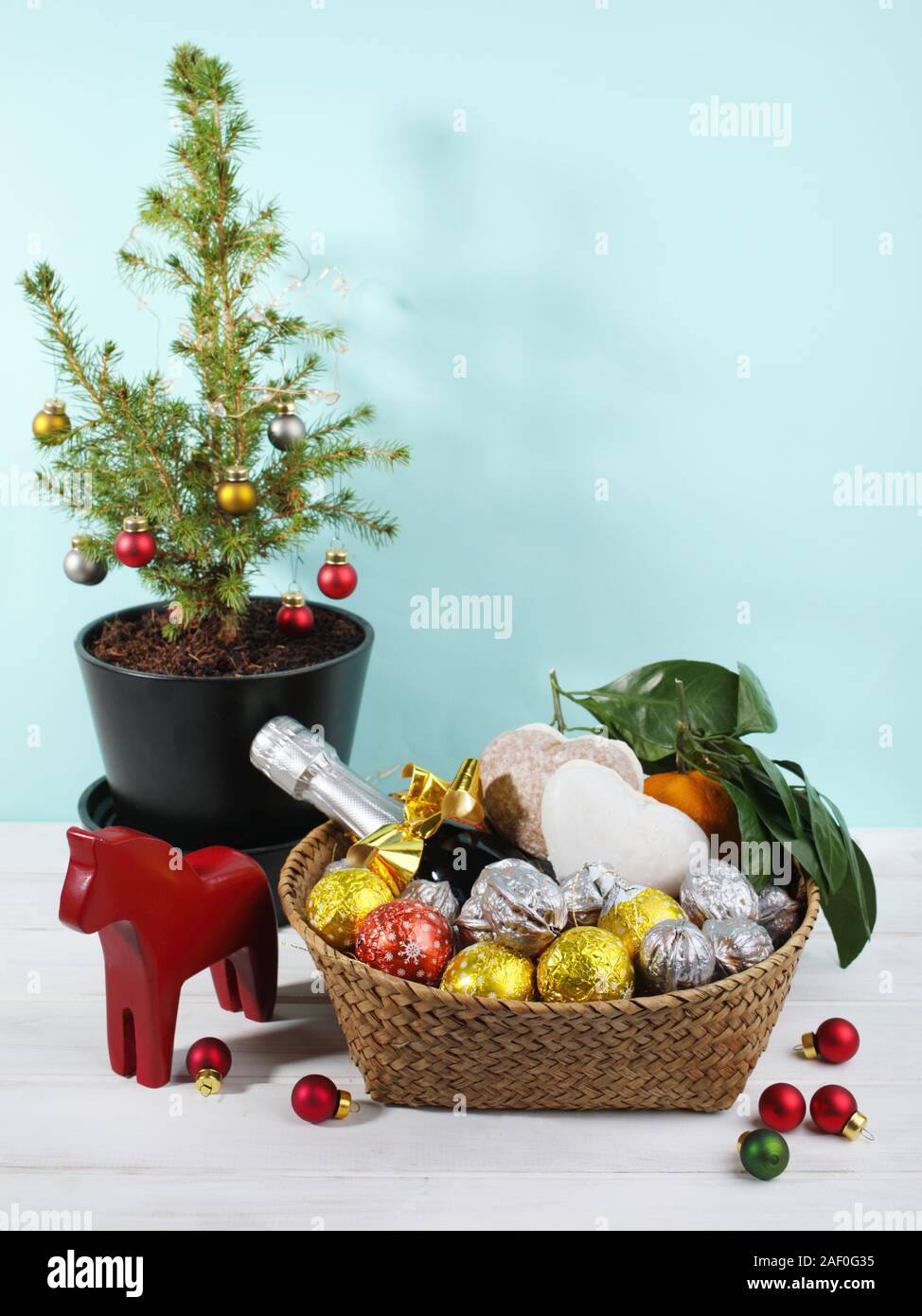 Panier cadeau de Noël avec des confiseries au chocolat, noix, épices, mandarines, une bouteille de champagne, une statue de Cheval de Dala suédois, et les petits Banque D'Images Panier cadeau de Noël avec des confiseries au chocolat, noix, épices, mandarines, une bouteille de champagne, une statue de Cheval de Dala suédois, et les petits Banque D'Images