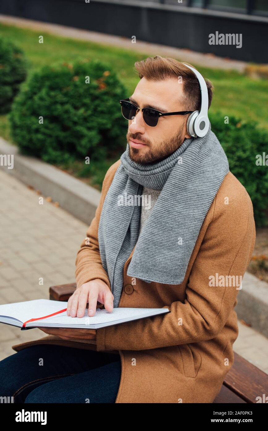 Aveugle dans les écouteurs lecture livre avec braille font in park Banque D'Images