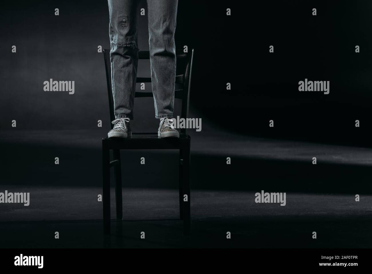 Portrait de l'auto-destructeur debout sur chaise et va se suicider sur fond noir Banque D'Images