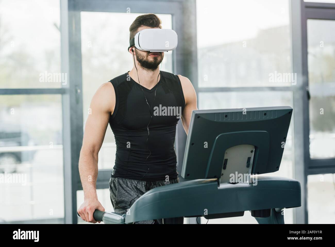 Sportsman dans casque de réalité virtuelle s'exécutant sur tapis roulant à  la salle de sport Photo Stock - Alamy