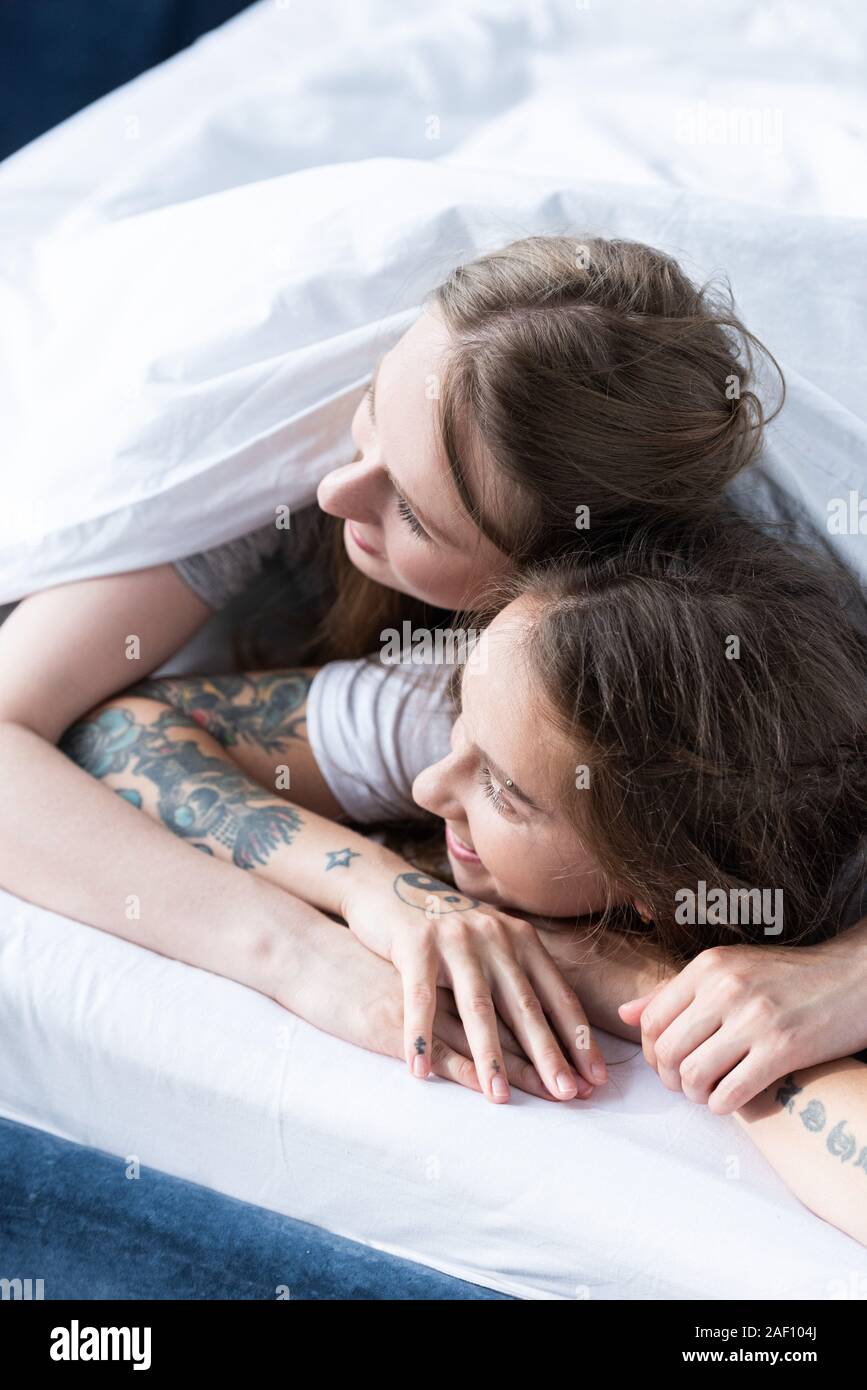 Deux lesbiennes tout en embrassant smiling couché sous couverture dans le  lit Photo Stock - Alamy