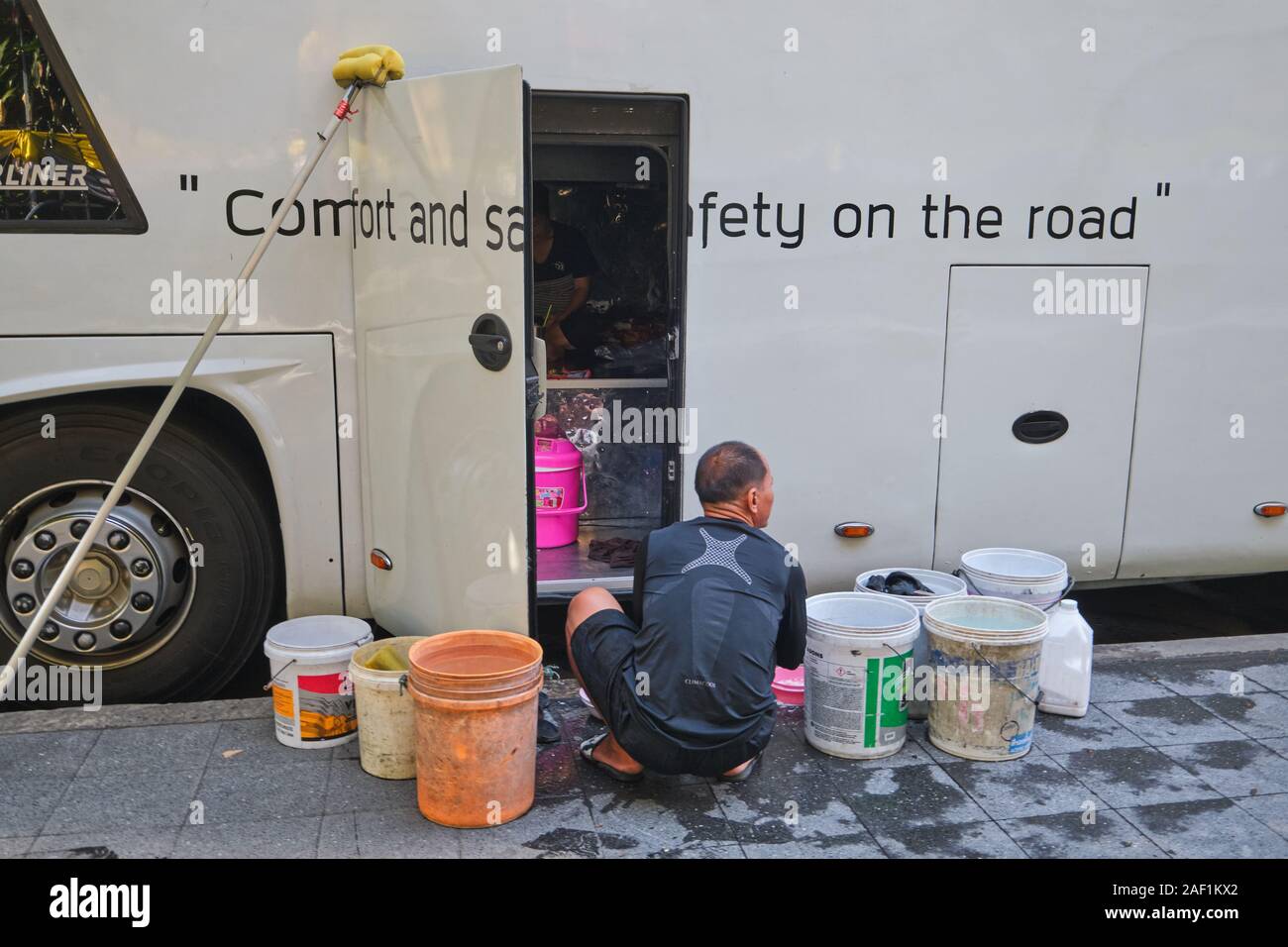 Un employé d'une compagnie de bus tour à Bangkok, Thaïlande - entreprise slogan 'Confort et sécurité sur la route" - faire un peu de nettoyage et rangement Banque D'Images