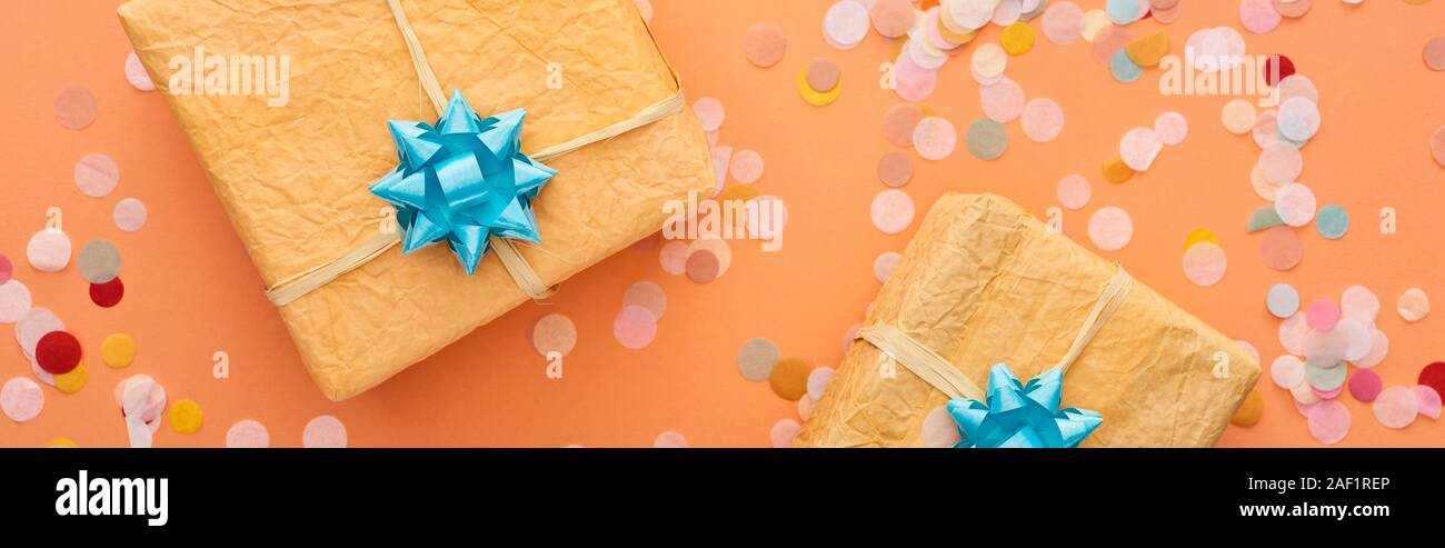 Bleu de arcs sur des boîtes de cadeaux près de confettis sur orange Banque D'Images