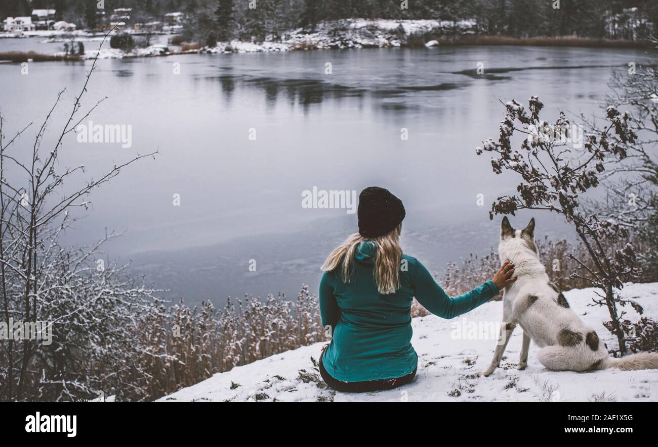 Femme avec chien assis au bord du lac Banque D'Images