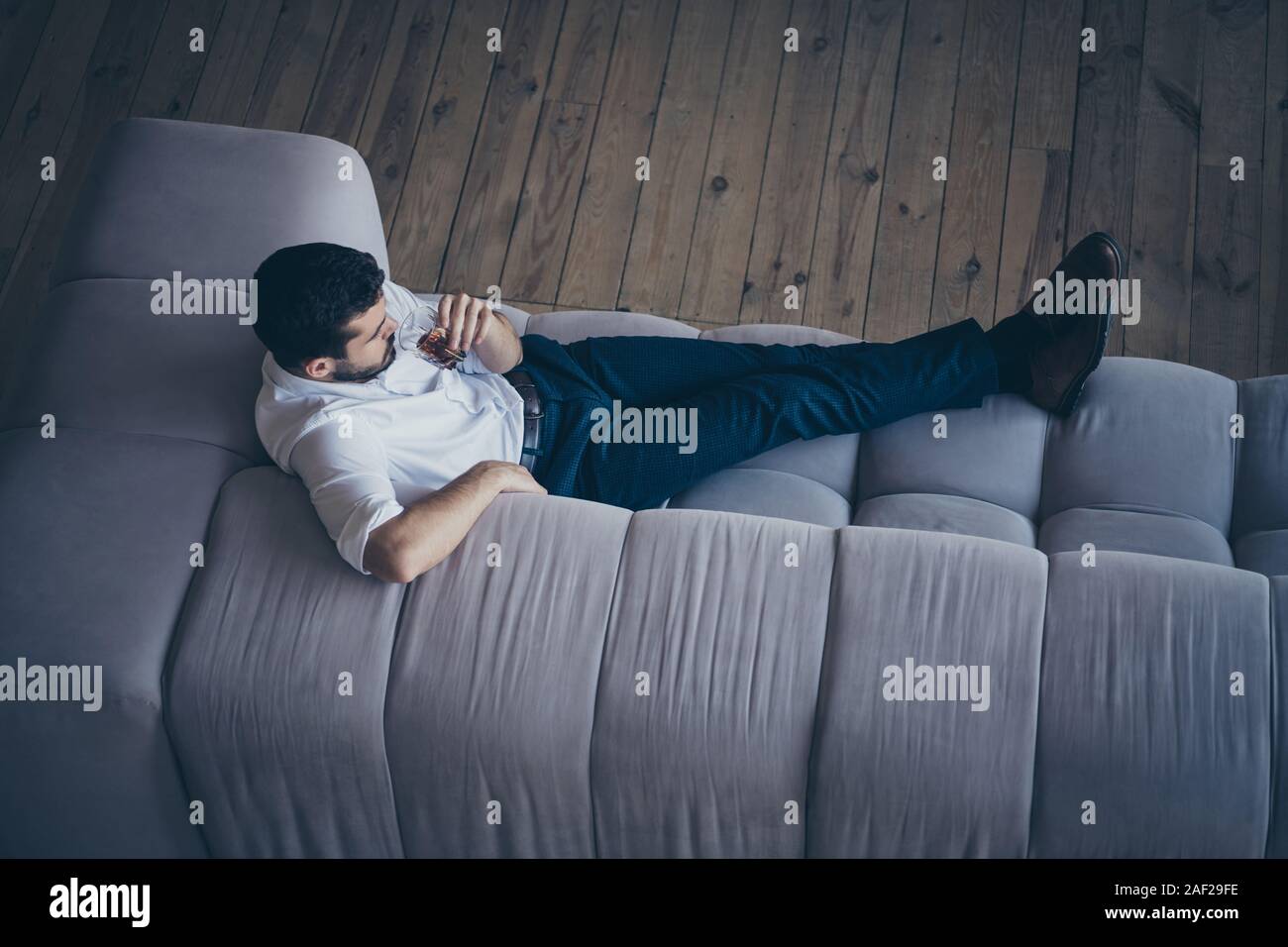 Haut de au-dessus de sa belle il l'imposition attrayante guy couché sur le divan confortable boisson potable soirée libre de dépenser temps libre à l'espace ouvert Banque D'Images