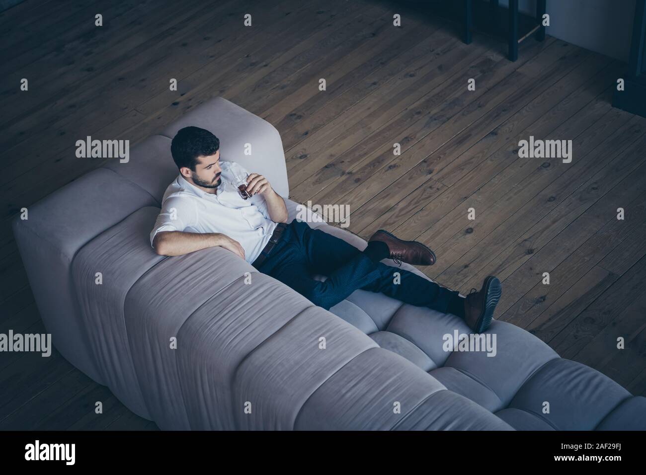 Haut de au-dessus de sa belle il grave attrayant imposant guy allongé sur le divan de boisson potable ayant reste libre temps libre dans modern Banque D'Images