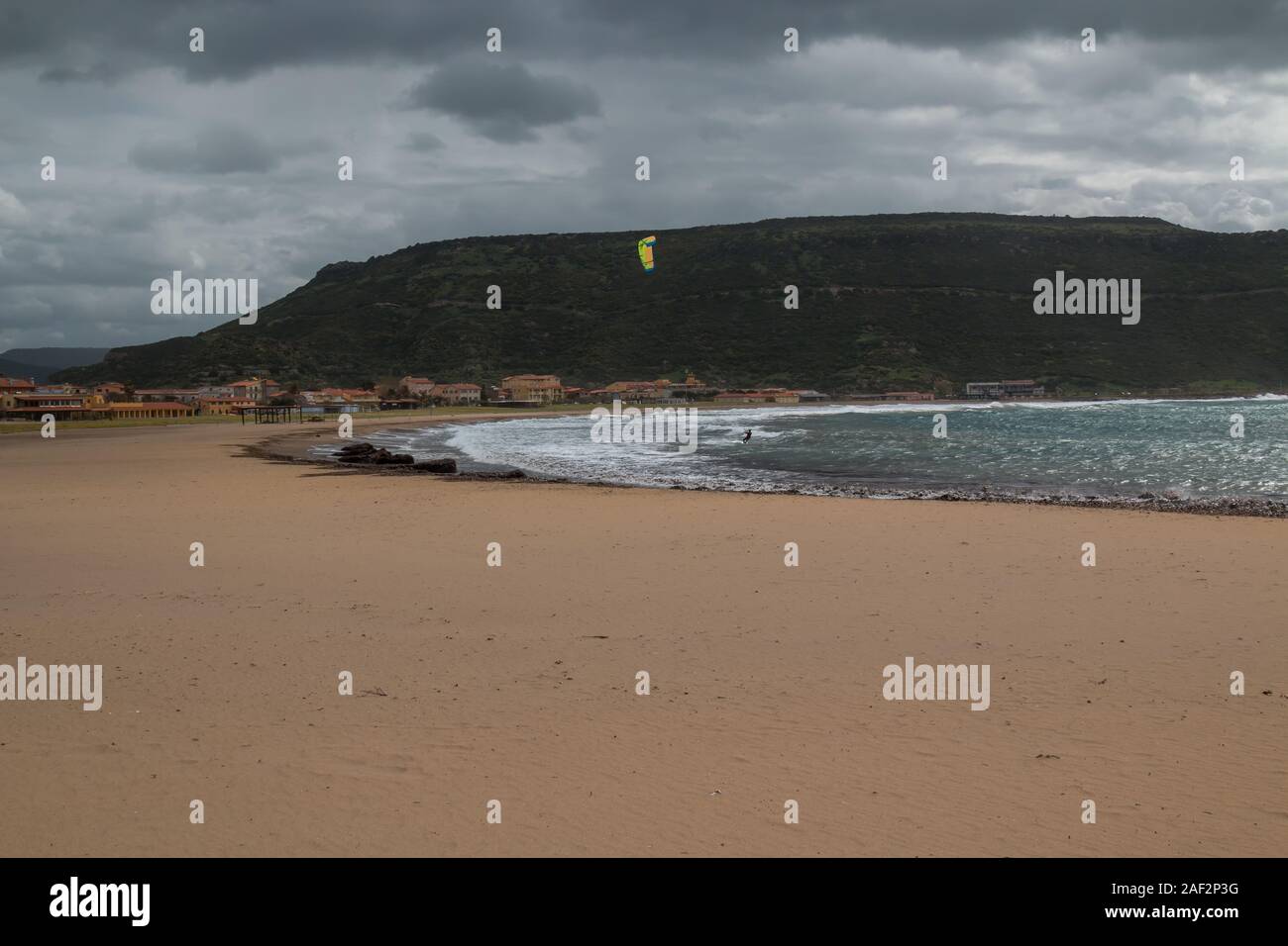 Sur la plage de sable jaune, doublure d'une baie de la mer Méditerranée. Montagne dans l'arrière-plan. Ciel nuageux orageux. Bosa Marina, Sardaigne, Italie. Banque D'Images