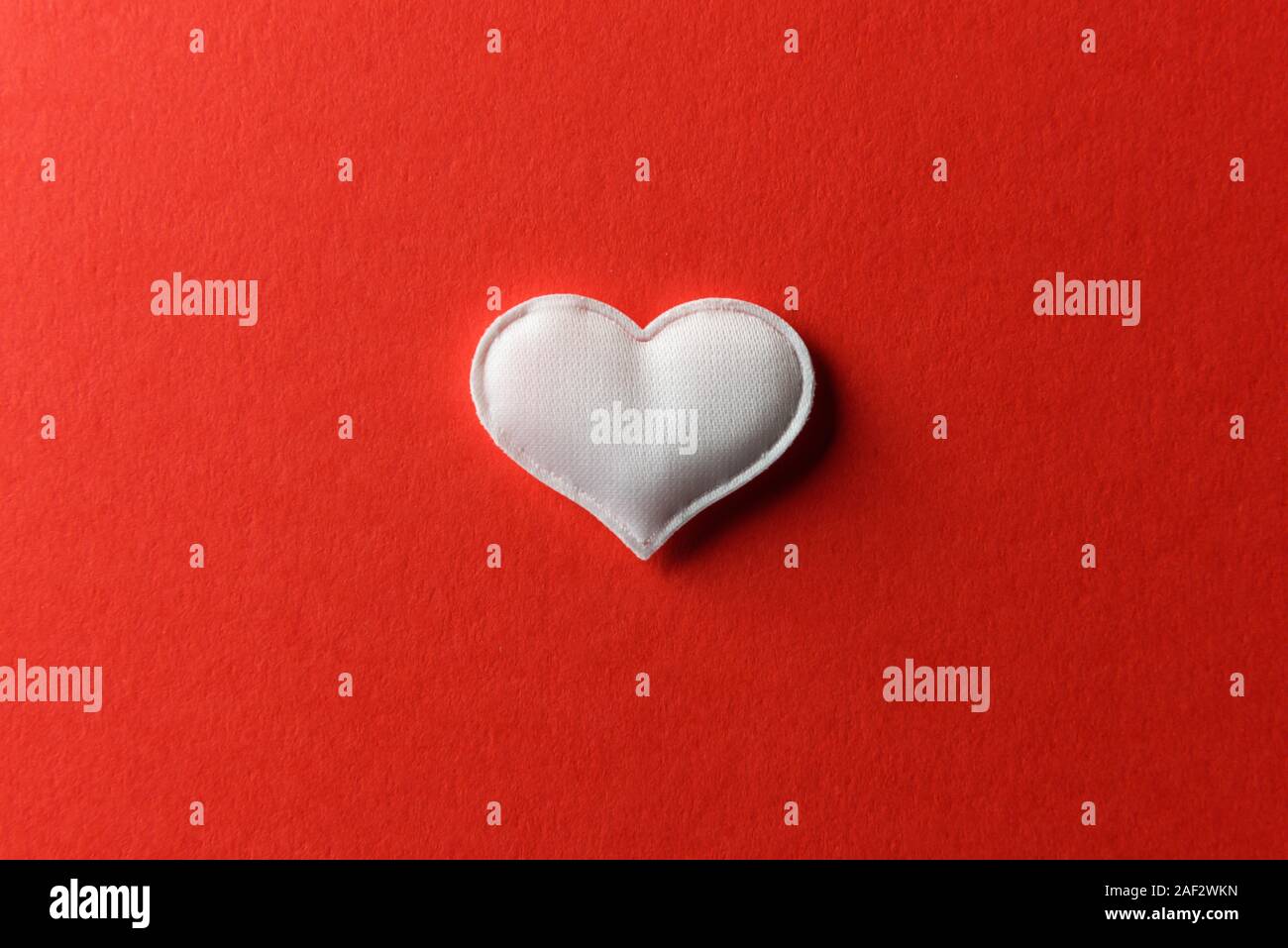 Coeur textile blanc sur fond rouge. La texture et de l'amour Saint-valentin concept Banque D'Images