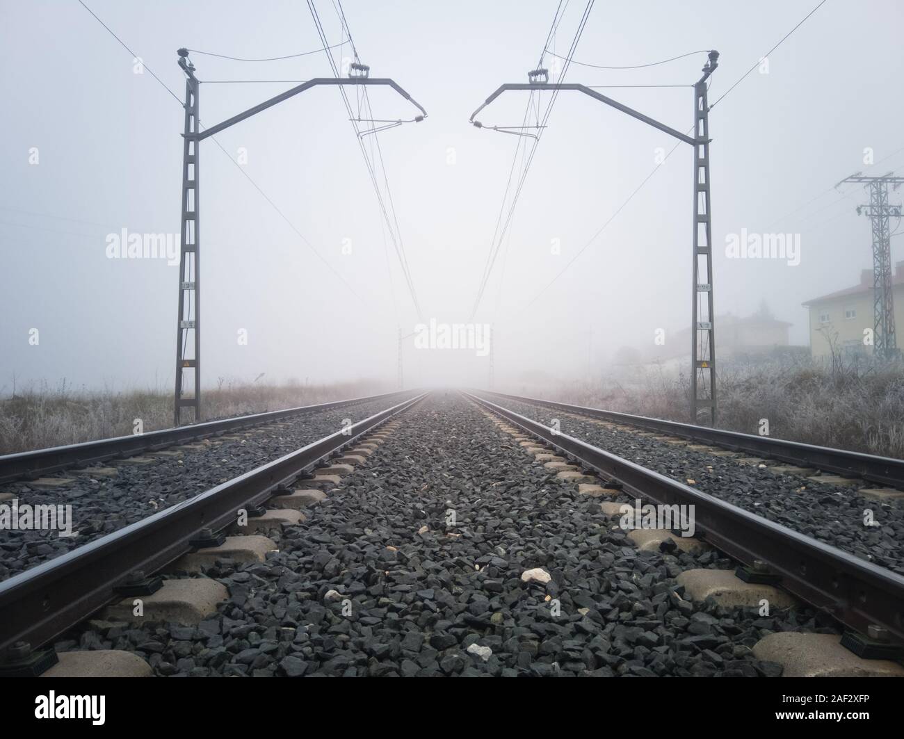 Les voies ferrées et de poteaux caténaires disparaître dans un épais brouillard. Concept de train Banque D'Images