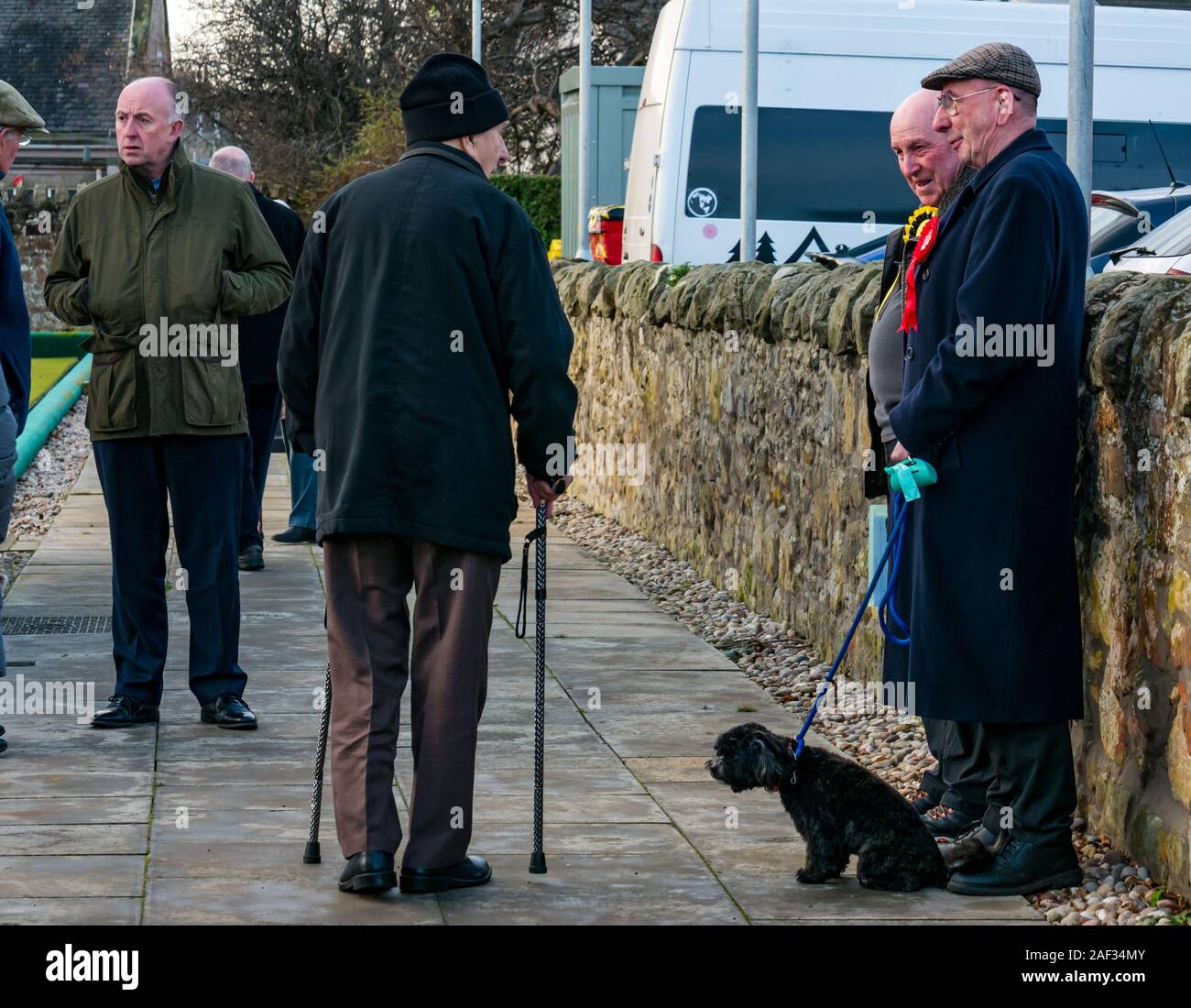 Gullane Bowling Club, East Lothian, Ecosse, Royaume-Uni, le 12 décembre 2019. Élections britanniques : les électeurs dans le bureau de vote local avec les militants locaux et un homme tenant un chien en laisse Banque D'Images