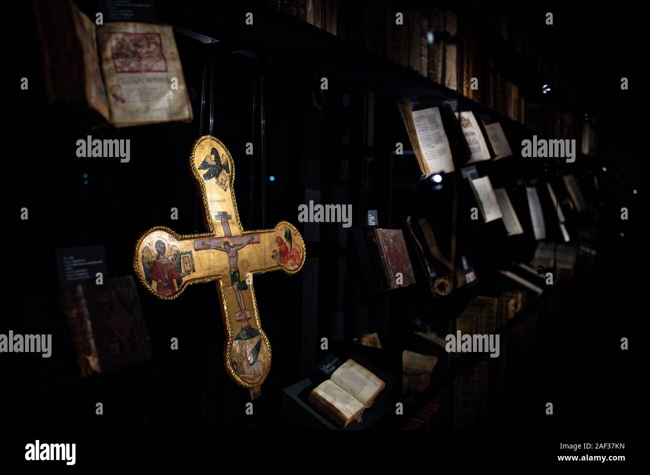 12 décembre 2019, en Rhénanie du Nord-Westphalie, Münster : Lors de l'aperçu de la Bible Museum de l'Université de Münster, un 15e siècle doré croix avec la crucifixion de Jésus le Christ et les symboles des quatre évangélistes se bloque derrière le verre à côté de nombreuses bibles. Après cinq ans et demi de la reconstruction, le Musée de la Bible s'ouvre à l'Université de Münster avec ses quelque 1500 pièces. L'une des plus importantes pièces de la collection est une Bible de Luther dédiée à l'réformateur de les derniers jours de sa vie. En outre, la langue ancienne 650 bibles de l 'Walter Re Banque D'Images
