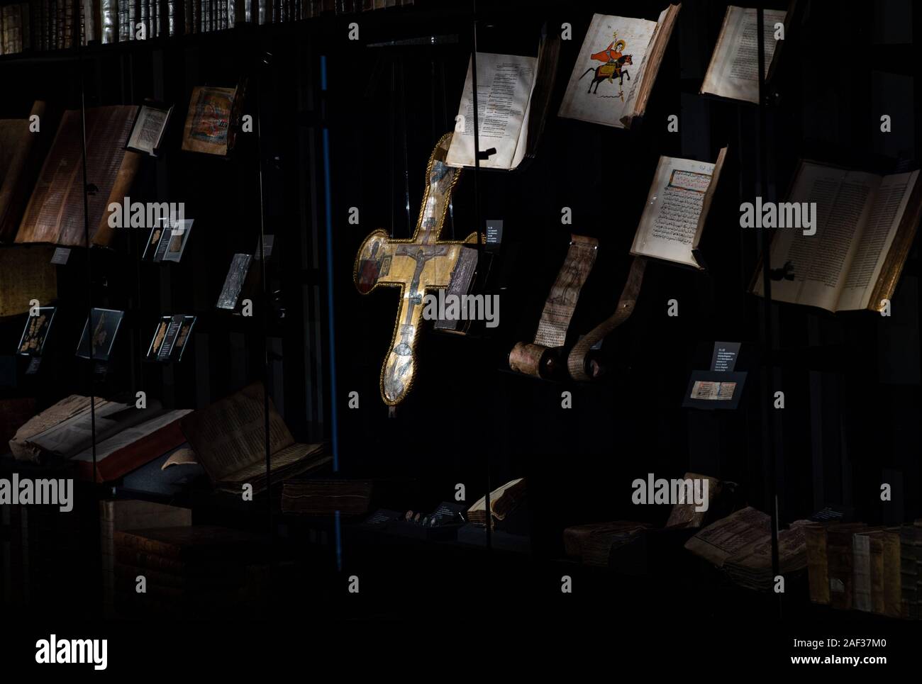 12 décembre 2019, en Rhénanie du Nord-Westphalie, Münster : Lors de l'aperçu de la Bible Museum de l'Université de Münster, un 15e siècle doré croix avec la crucifixion de Jésus le Christ et les symboles des quatre évangélistes se bloque derrière le verre à côté de nombreuses bibles. Après cinq ans et demi de la reconstruction, le Musée de la Bible s'ouvre à l'Université de Münster avec ses quelque 1500 pièces. L'une des plus importantes pièces de la collection est une Bible de Luther dédiée à l'réformateur de les derniers jours de sa vie. En outre, la langue ancienne 650 bibles de l 'Walter Re Banque D'Images