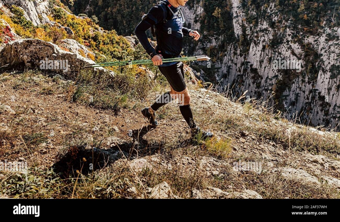 Homme coureur avec les bâtons de trekking courir bord de falaise course de montagne Banque D'Images