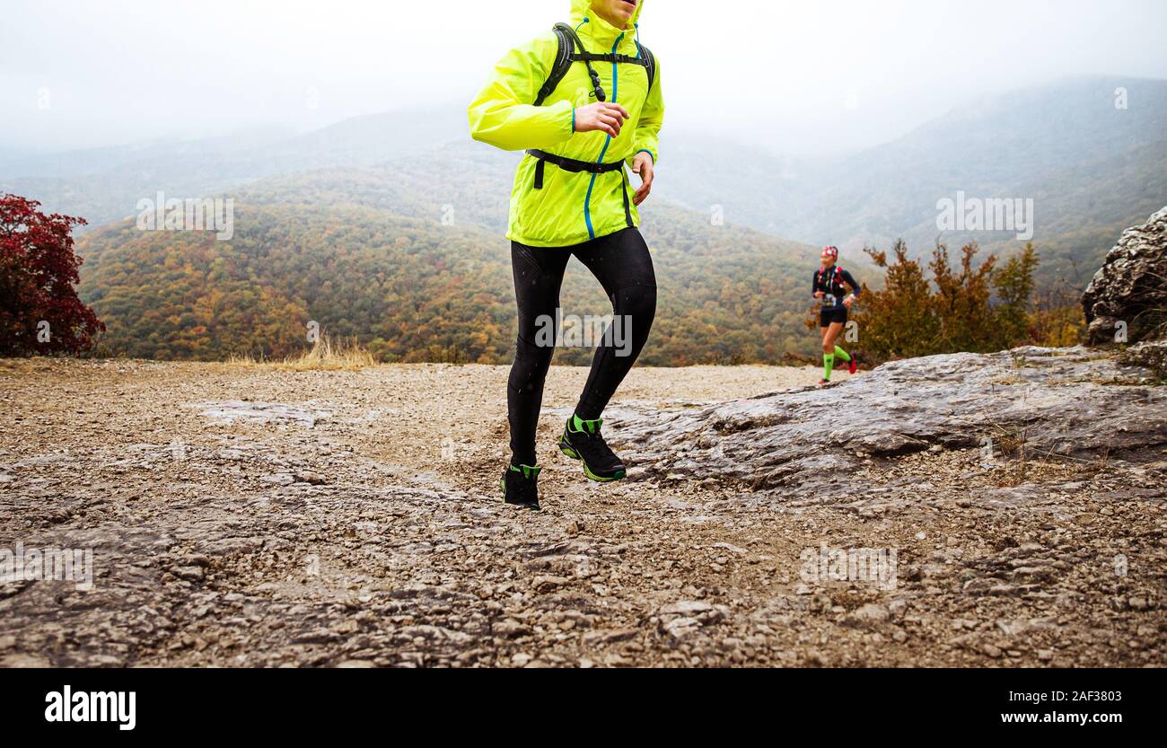 L'homme à yellow jacket mountain trail running par temps de pluie Banque D'Images L'homme à yellow jacket mountain trail running par temps de pluie Banque D'Images