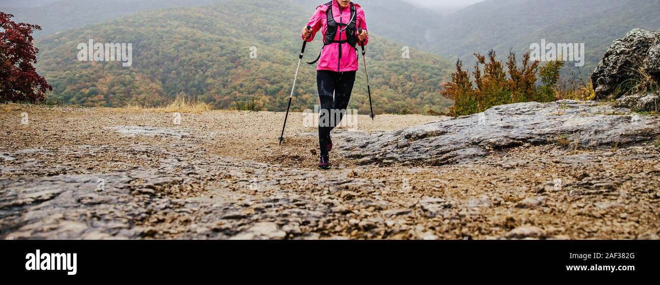 Femme avec les bâtons de trekking sous mountain trail en automne météo Banque D'Images