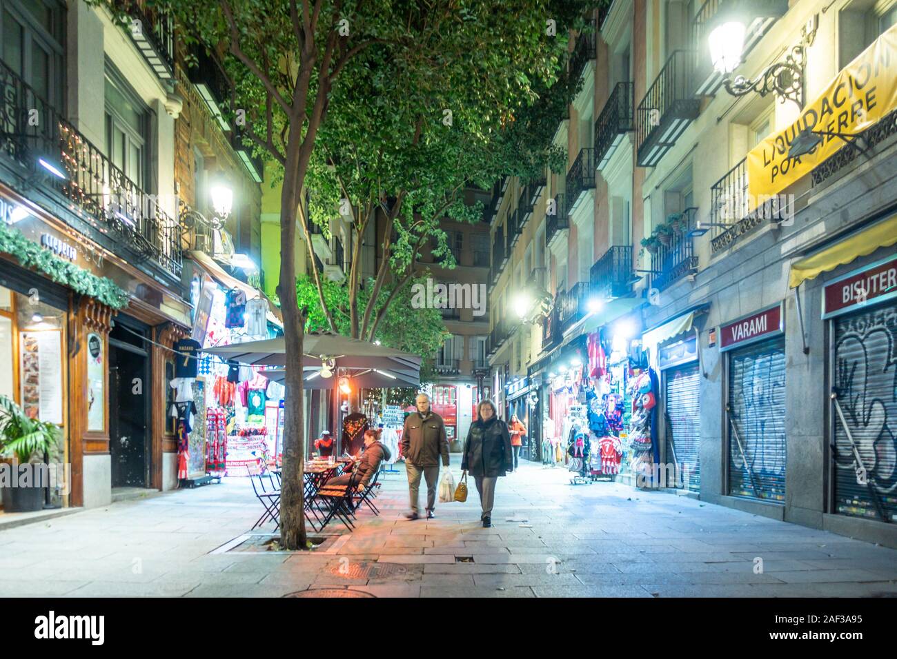 Vue sur une rue du centre-ville appelée Calle de Postas à Madrid, Espagne la nuit. Exécuter les arbres au milieu de la rue qui est éclairé par des lumières. Banque D'Images