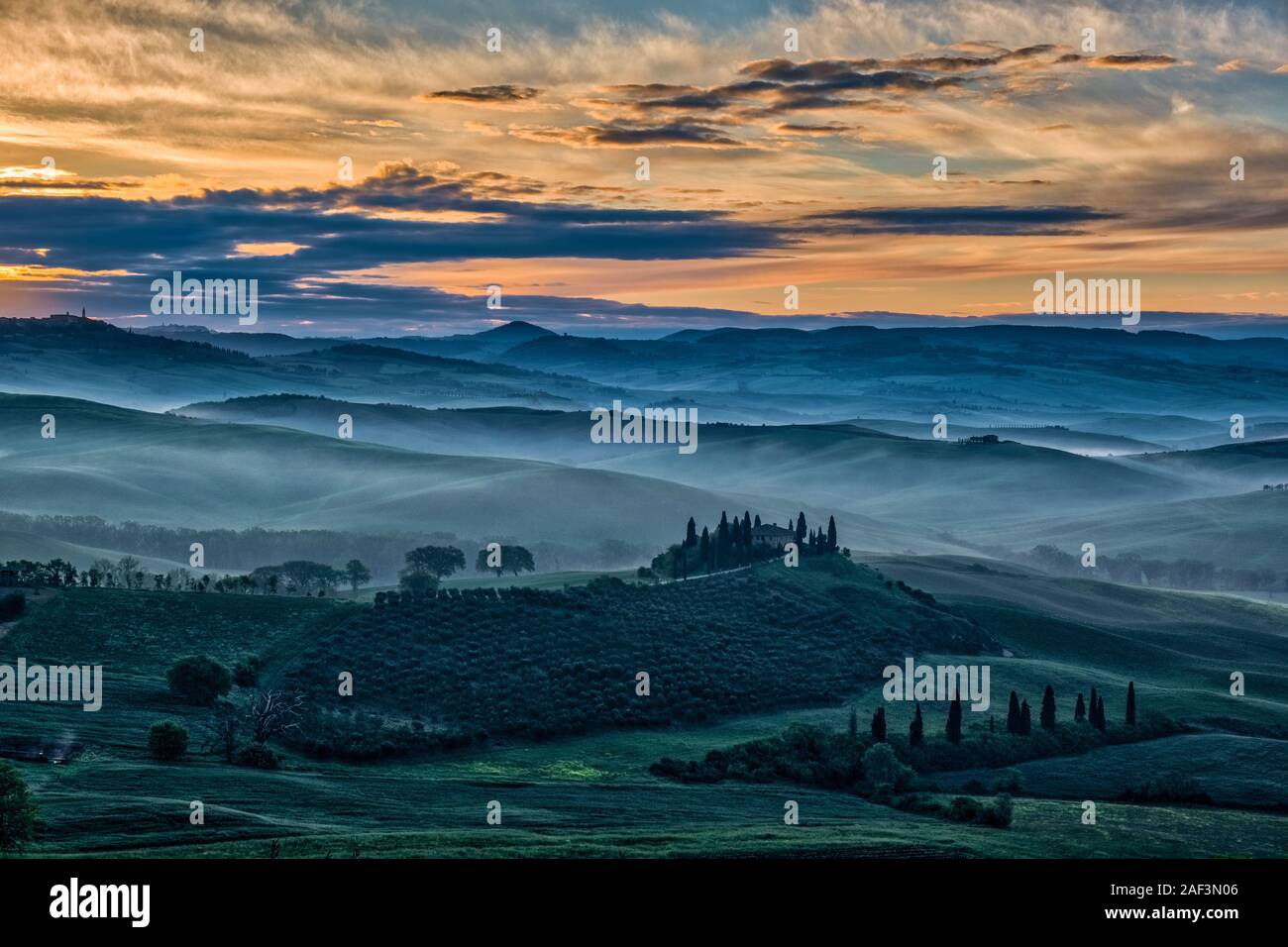 Vallonné typique campagne toscane, dans le Val d'Orcia, la ferme Podere Belvedere sur une petite colline et de brouillard dans les vallées, au lever du soleil Banque D'Images