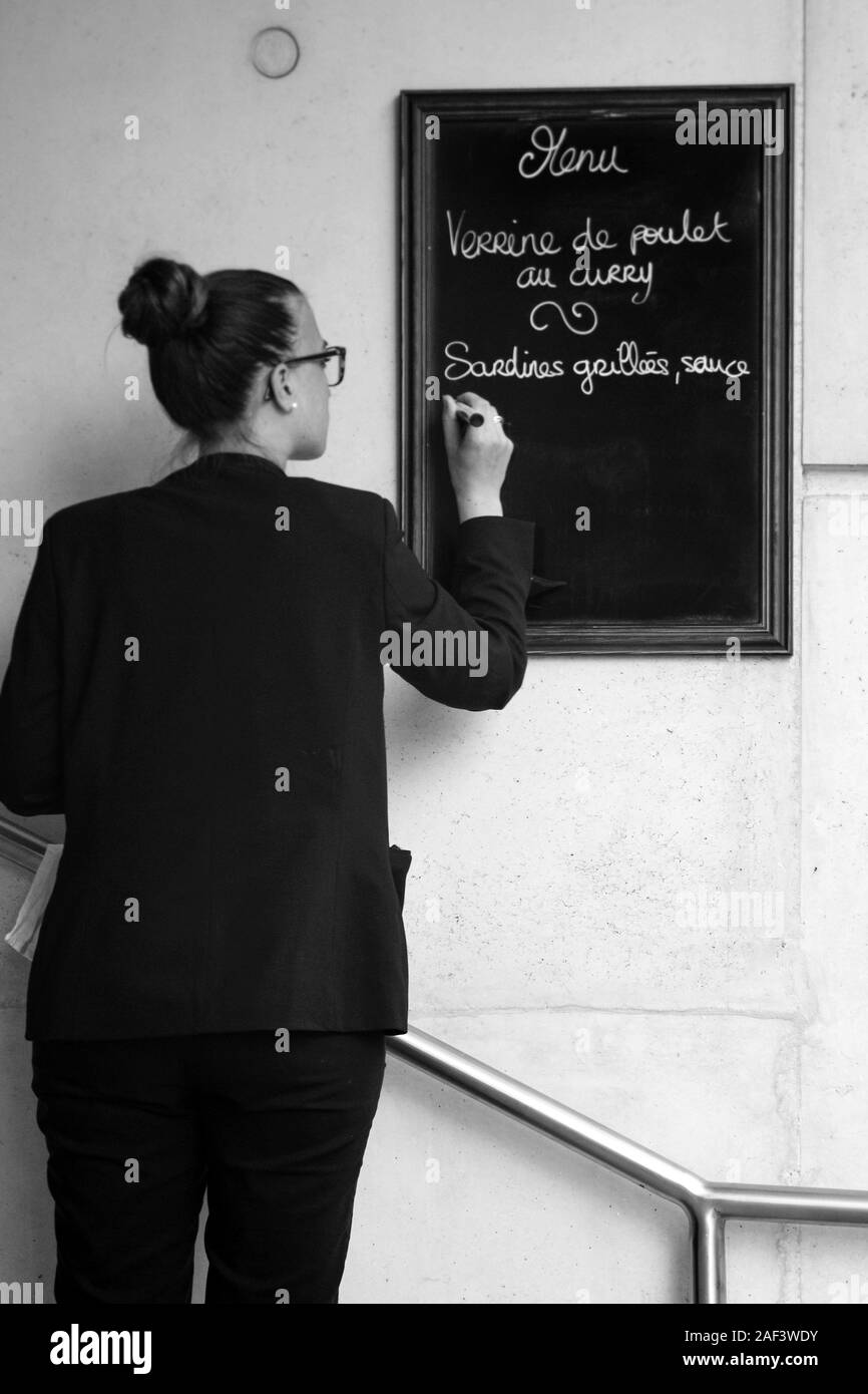 Image en noir et blanc de la jeune femme écrit restaurant menu déjeuner sur tableau noir à Paris, France Banque D'Images