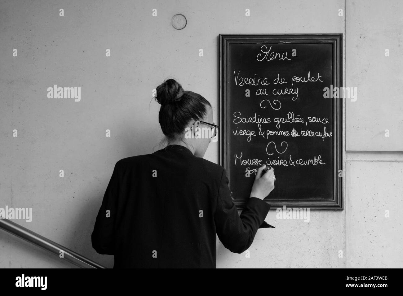 Image Monochrome de jeune femme écrit le déjeuner menu sur tableau noir à Paris, France Banque D'Images