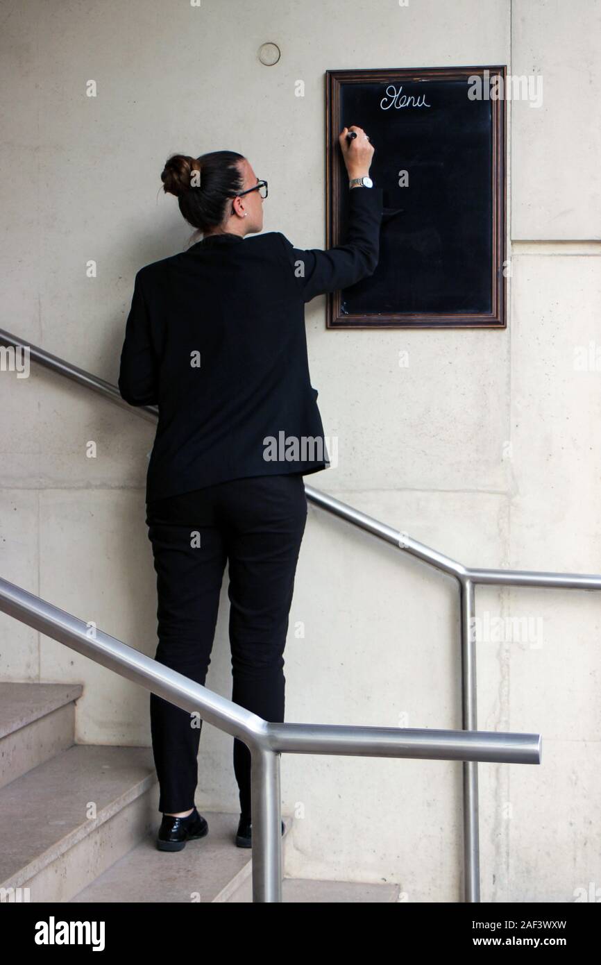 Jeune femme écrit restaurant menu déjeuner sur tableau noir sign in Paris, France Banque D'Images