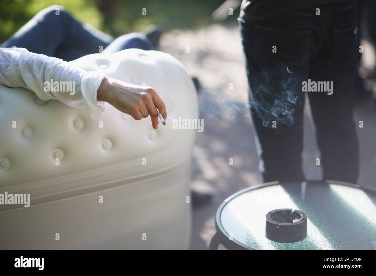Main d'un homme avec une cigarette dans une zone fumeurs du restaurant Banque D'Images