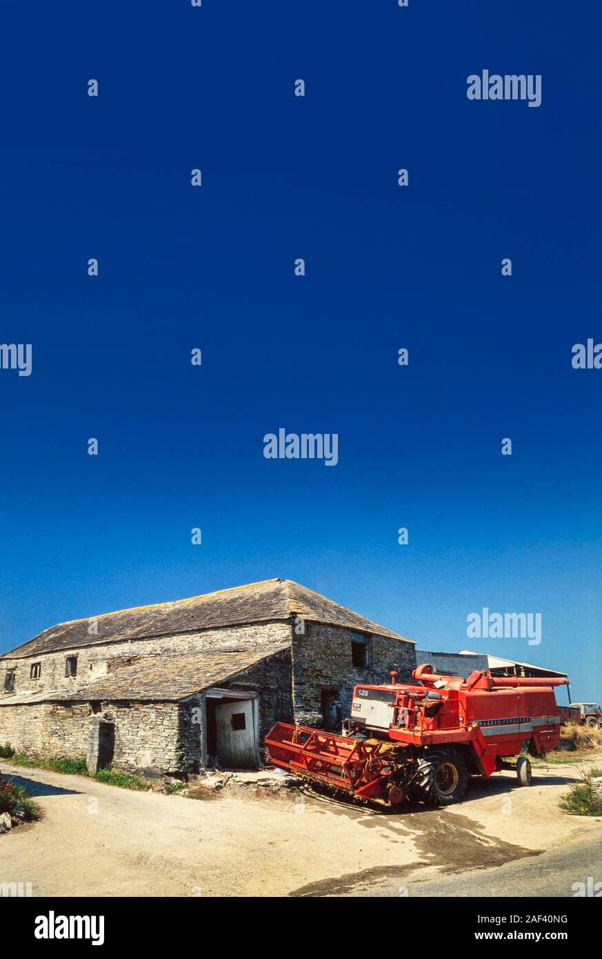 Moissonneuse-batteuse avec des bâtiments de ferme, ciel bleu Banque D'Images