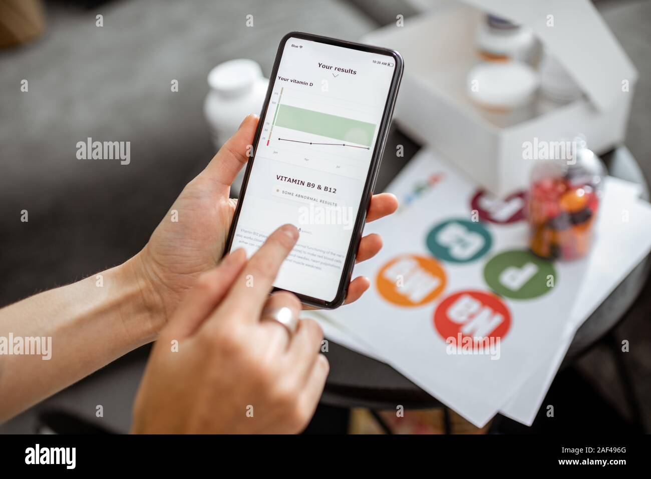 Contrôle de la femme suite de tests médicaux sur un smartphone, close-up avec des suppléments nutritionnels sur l'arrière-plan. Concept de l'individu en ligne Sélection de suppléments alimentaires Banque D'Images