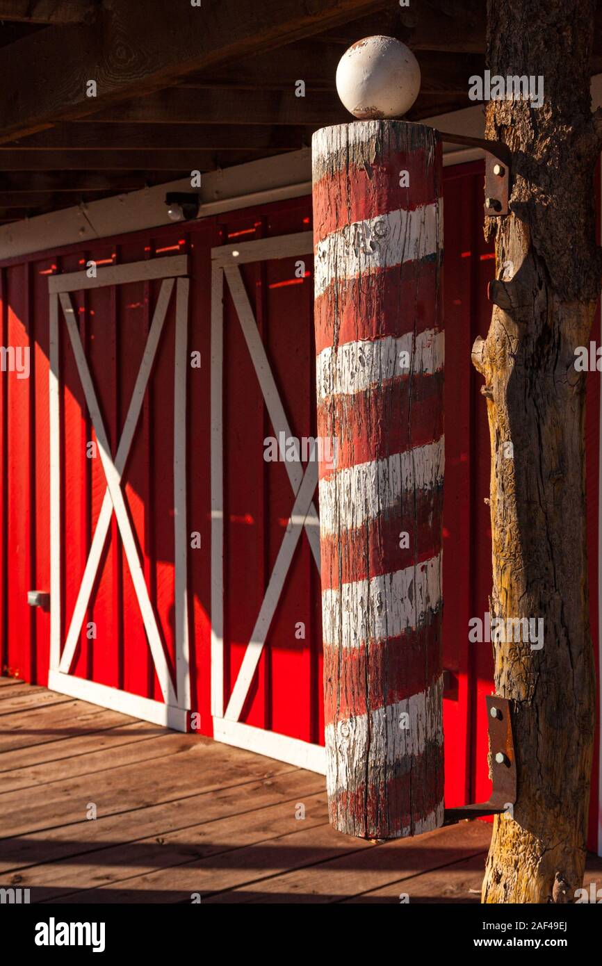 Une vieille enseigne de barbier rouge et blanc en face de doubles portes de grange sur l'ancienne route 66 à Seligman, Arizona Banque D'Images