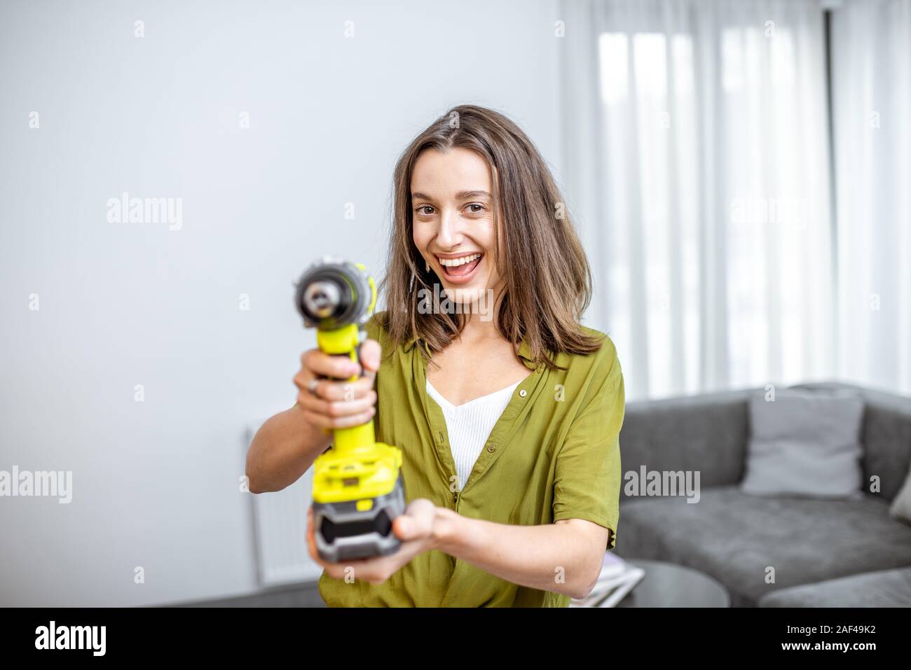 Portrait d'un jeune et heureux handywoman avec tournevis sans fil à la maison. Concept d'un ménage facile travailler avec des outils de travail modernes Banque D'Images