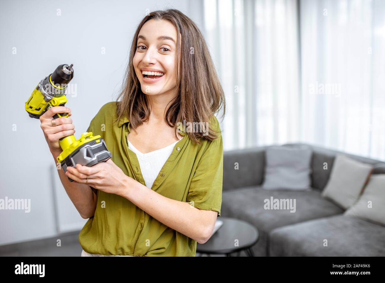 Portrait d'un jeune et heureux handywoman avec tournevis sans fil à la maison. Concept d'un ménage facile travailler avec des outils de travail modernes Banque D'Images