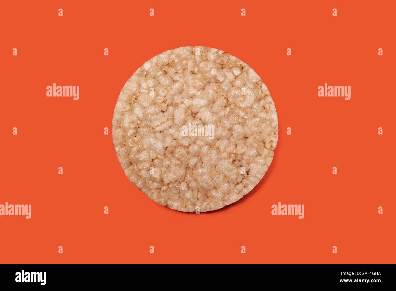 L'un des biscuits de riz ou de maïs dans le centre sur un fond de couleur orange-carotte, vue de dessus seul cookie croustillant pour la conception et l'alimentation saine alimentation, copier sp Banque D'Images