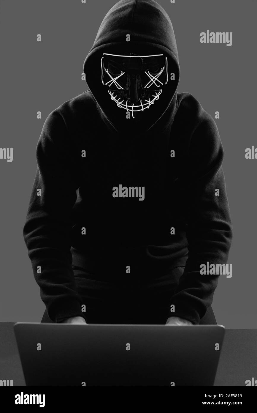 Portrait d'un homme anonyme dans un sweat noir et masque de néon l'intrusion dans un ordinateur. Studio shot. Banque D'Images