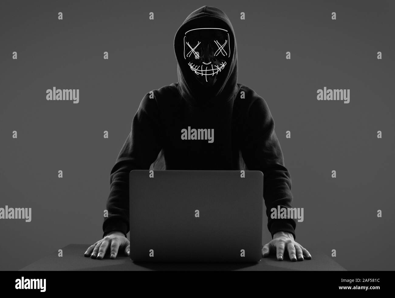 Portrait d'un homme anonyme dans un sweat noir et masque de néon l'intrusion dans un ordinateur. Studio shot. Banque D'Images