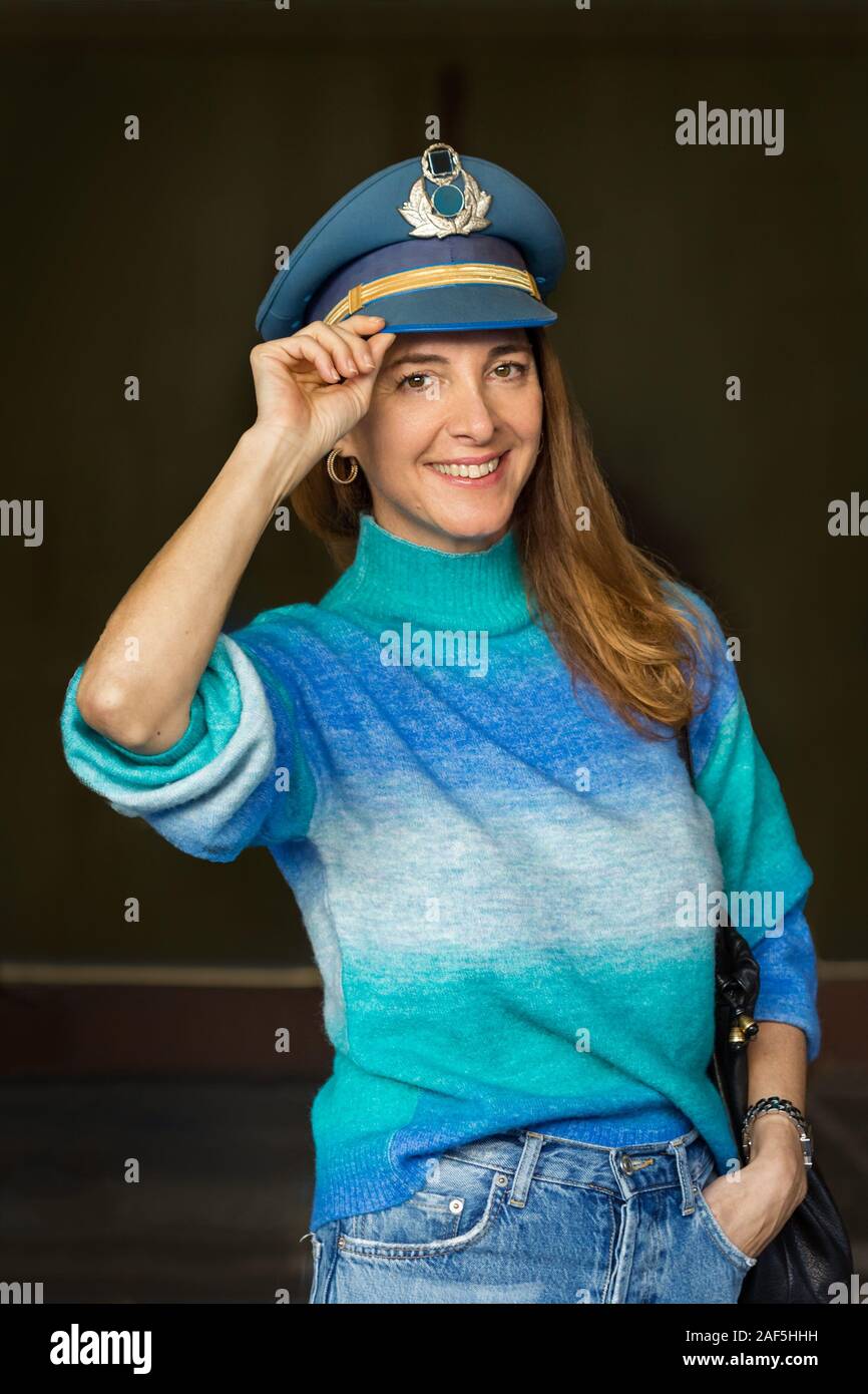Portrait of a senior woman saluting portant un chapeau militaire couleur menthe et sweter. Banque D'Images