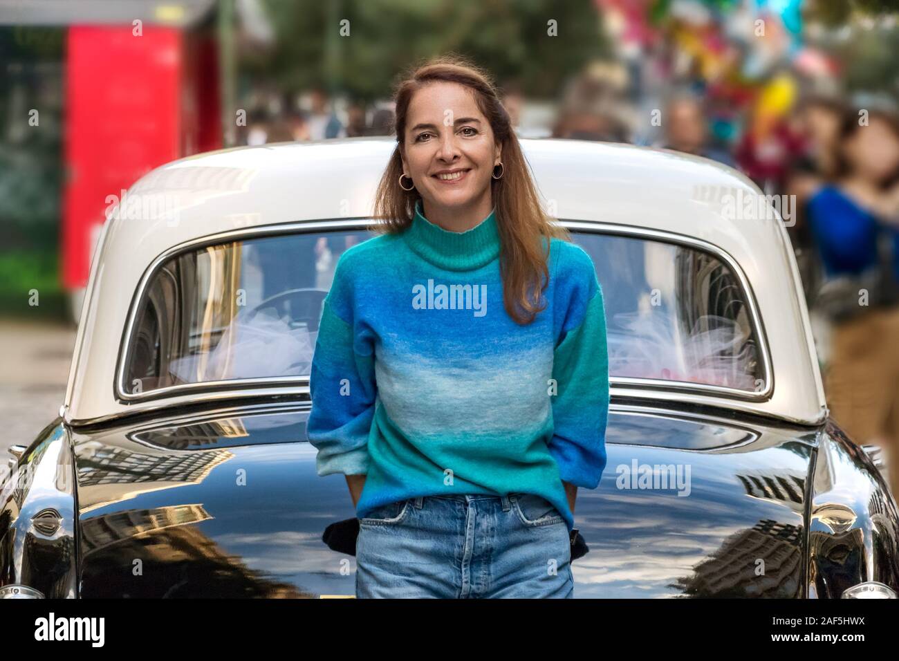 Portrait of a senior woman smiling, appuyé contre une voiture d'époque. Banque D'Images