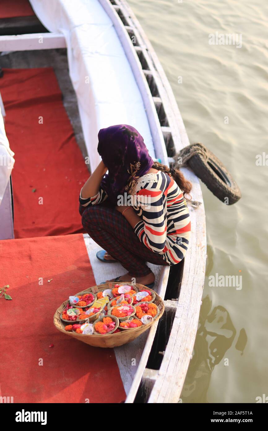 Une jeune fille assise sur le bateau avec un panier plein de fleurs Banque D'Images