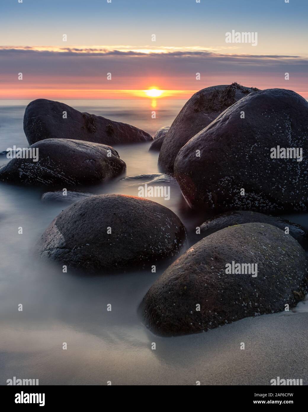 Magnifique coucher de soleil avec le sable de la plage et de l'humeur des pierres sur soirée d'été dans l'île de Lofoten, Norvège Banque D'Images Magnifique coucher de soleil avec le sable de la plage et de l'humeur des pierres sur soirée d'été dans l'île de Lofoten, Norvège Banque D'Images