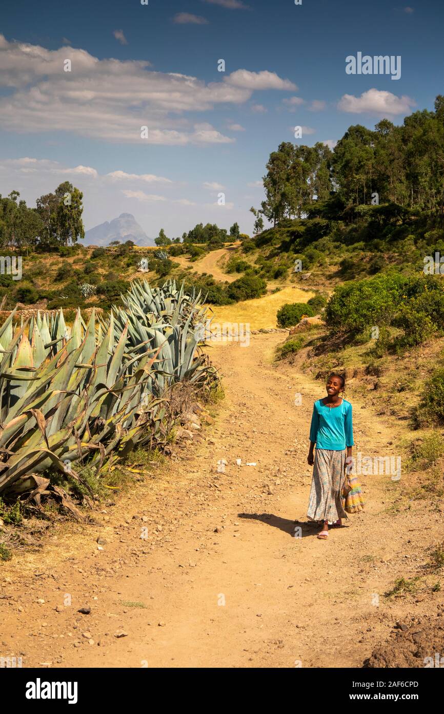 L'Éthiopie, du Tigré, Axoum Axoum (), Abalanicos, smiling girl walking along rural poussiéreuse route bordée d'énormes plantes d'aloès Banque D'Images