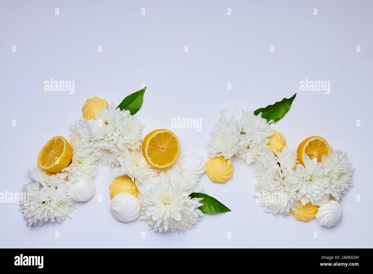 Un motif coloré avec des fleurs blanches, blanc et jaune merengues et la moitié des citrons. Copier l'espace. Banque D'Images