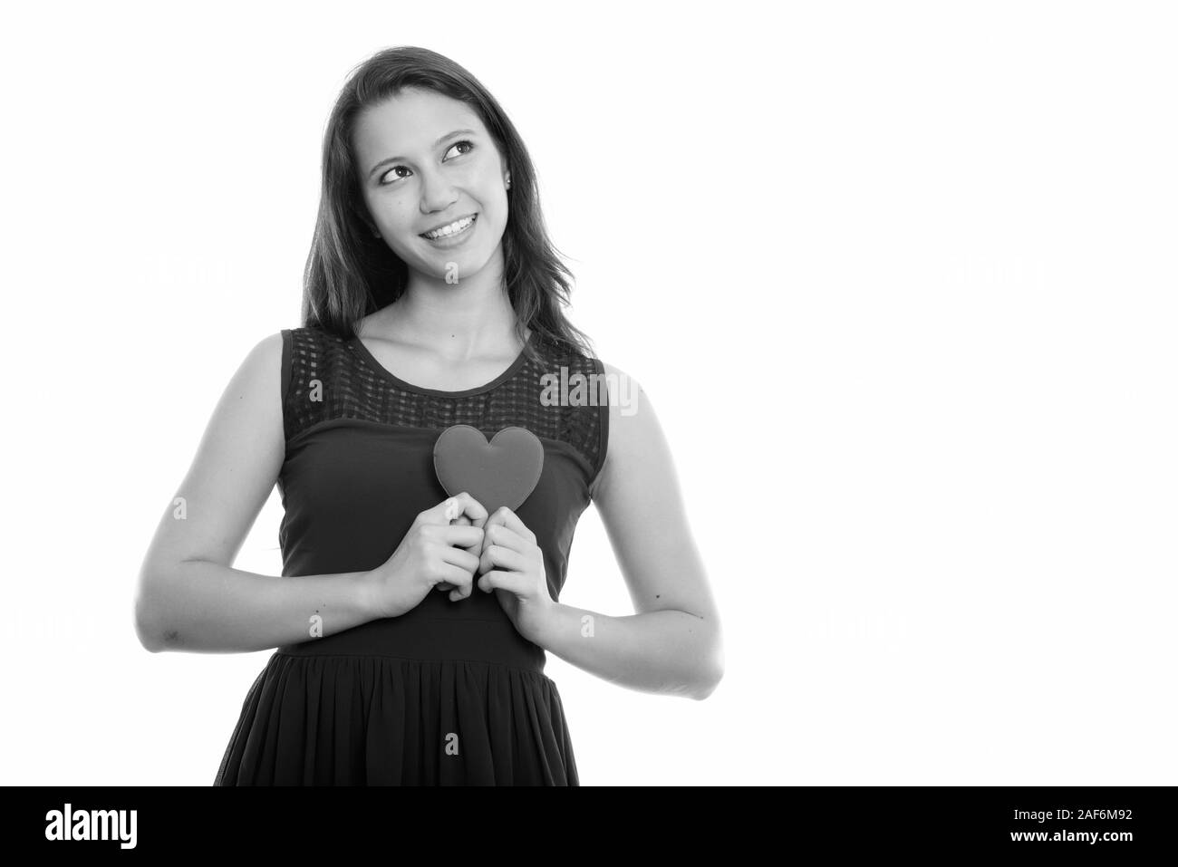 Portrait of happy young Beautiful woman smiling and holding red heart avec les deux mains en pensant Banque D'Images