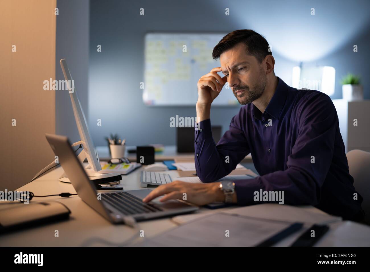 Comptable a souligné assis avec tête en main en travaillant à la fin de l'Office de Tourisme Banque D'Images
