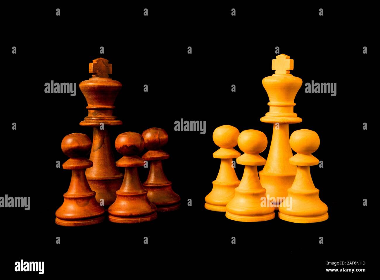 Vs noir blanc. Deux groupes qui s'opposent à l'autre. Diviser pour régner (diviser pour régner) concept. Échecs standards morceau en bois sur fond noir Banque D'Images