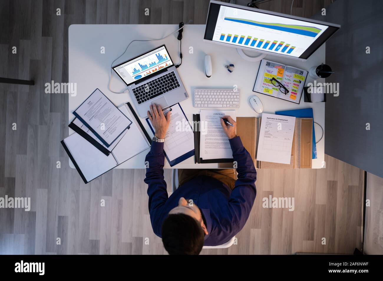 Mid adult businessman travaillant tard At Desk In Office Banque D'Images