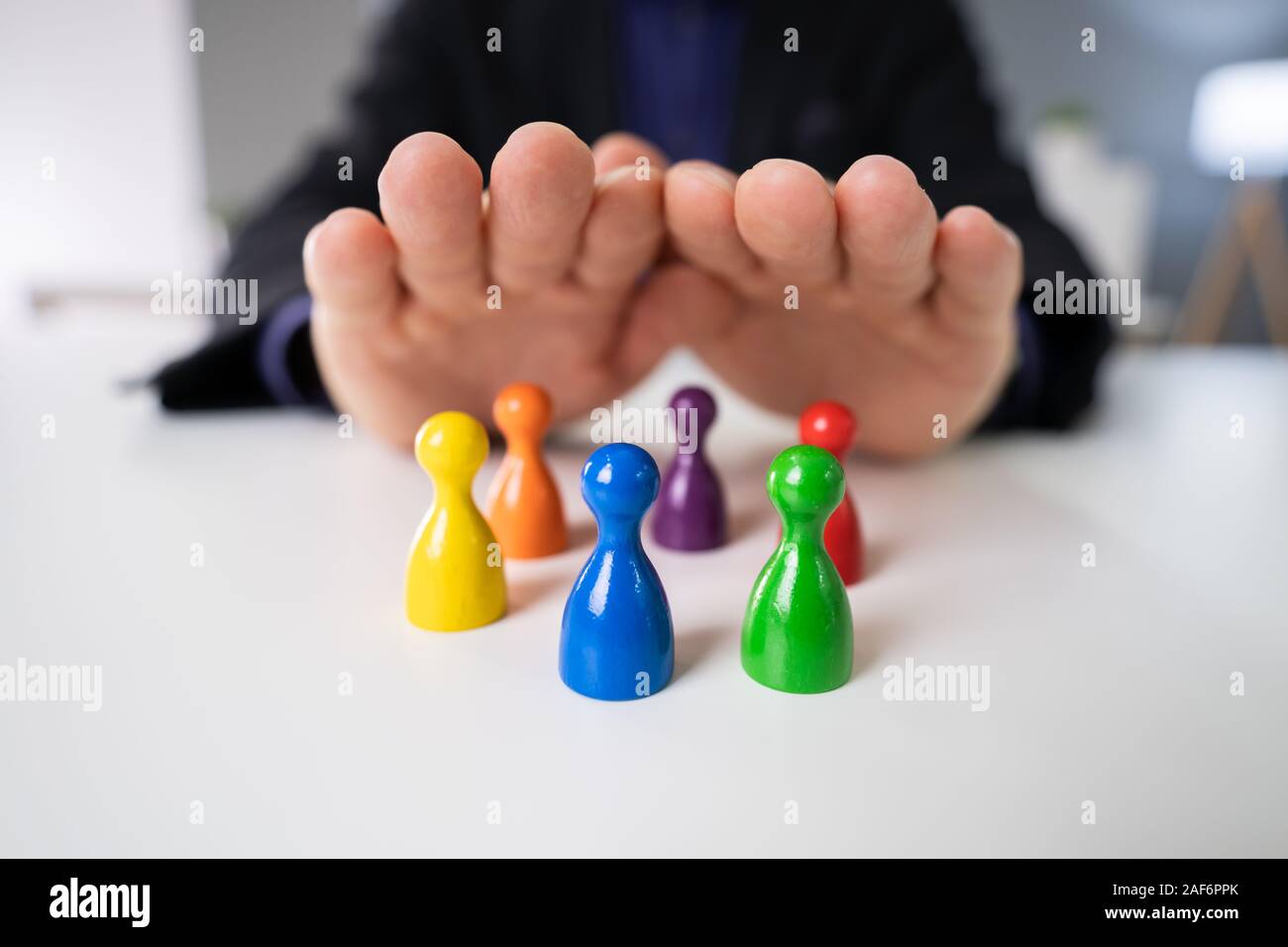 La main de la personne la protection des pions multicolores sur blanc 24 Banque D'Images