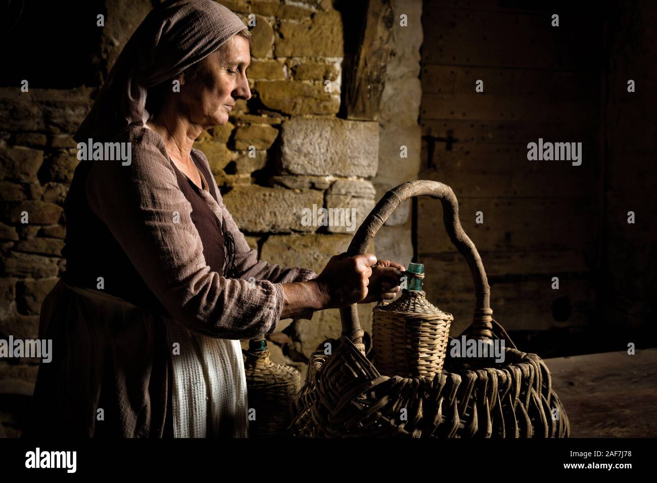 Femme en robe paysanne médiévale contrôler son panier alimentaire dans les caves d'un château médiéval authentique, libéré de la propriété en France Banque D'Images