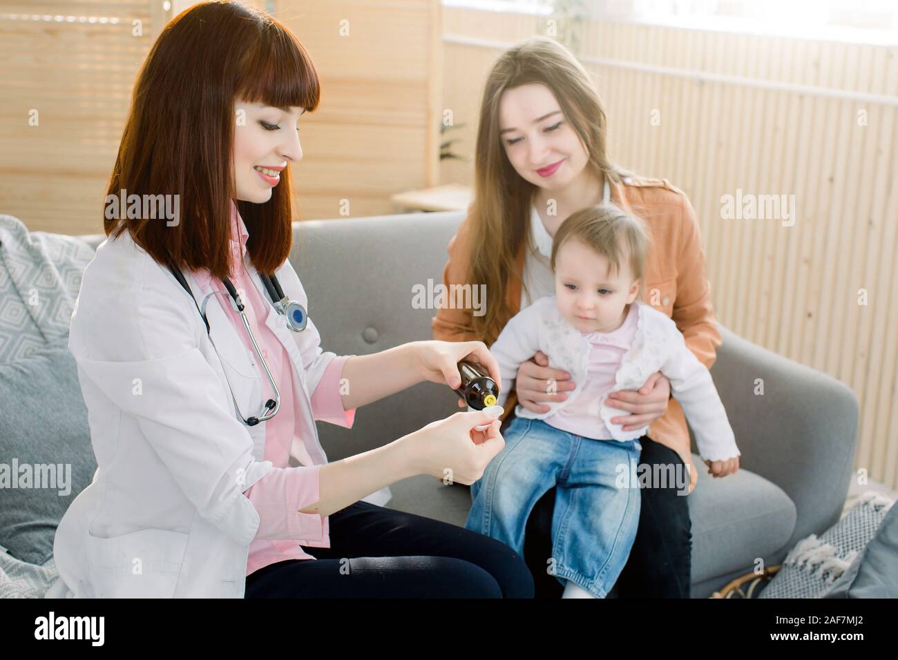 Petite fille accepte de boire le sirop de la médecine avec cuillère de médecin de famille à la maison Banque D'Images