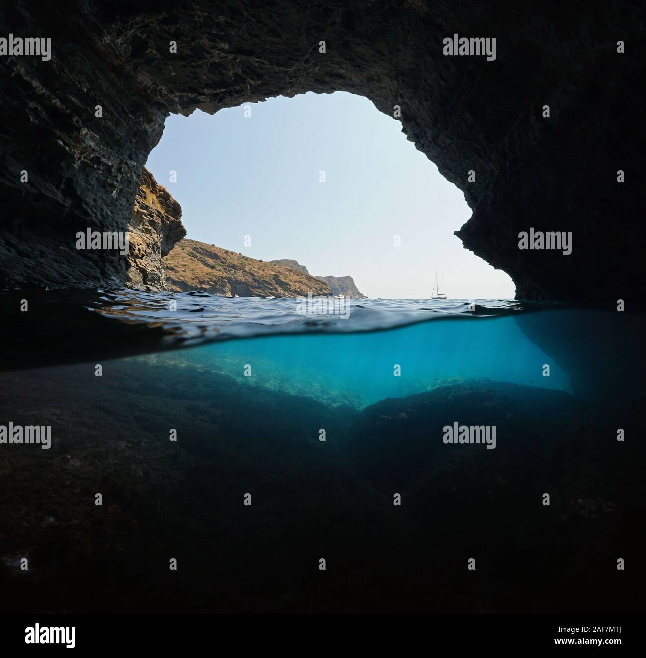 Côte Rocheuse avec quelques bateaux vu de l'intérieur d'une grande grotte, fractionnée sur et sous la surface de l'eau, mer Méditerranée, Espagne, Costa Brava, Catalogne Banque D'Images