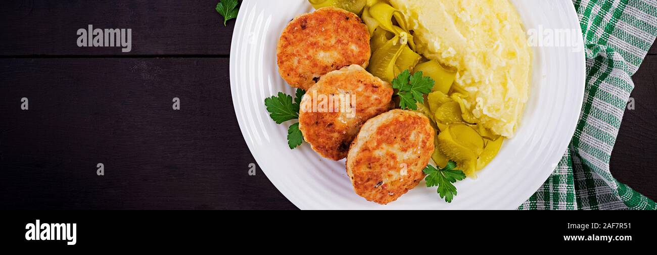 Des escalopes poêlées/boulettes avec de la purée de pommes de terre et cornichon sur plaque blanche. Vue de dessus, les frais généraux, la bannière Banque D'Images