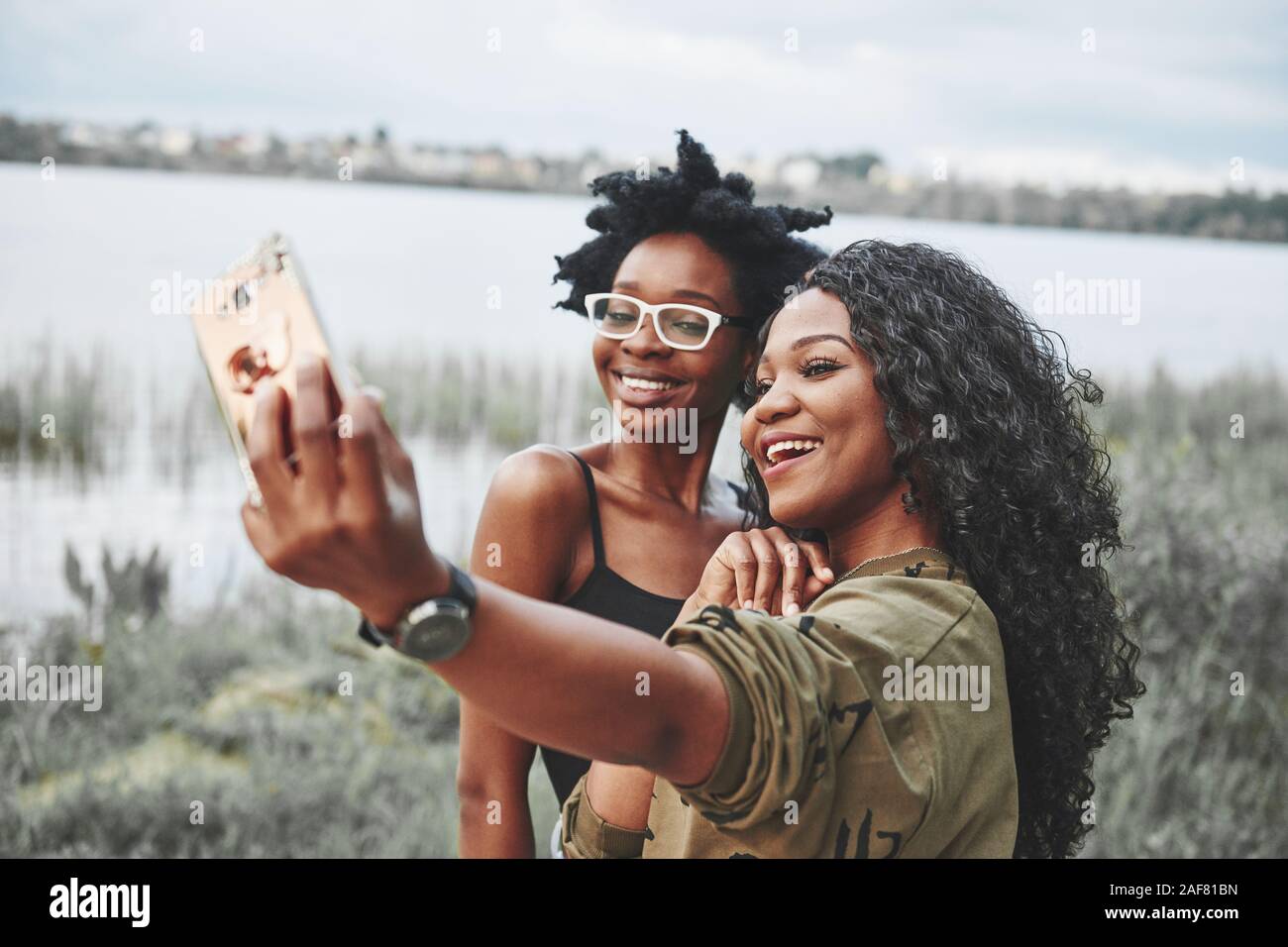 Deux femmes afro-américaines ont une promenade autour d'amis. Prendre des selfies Banque D'Images